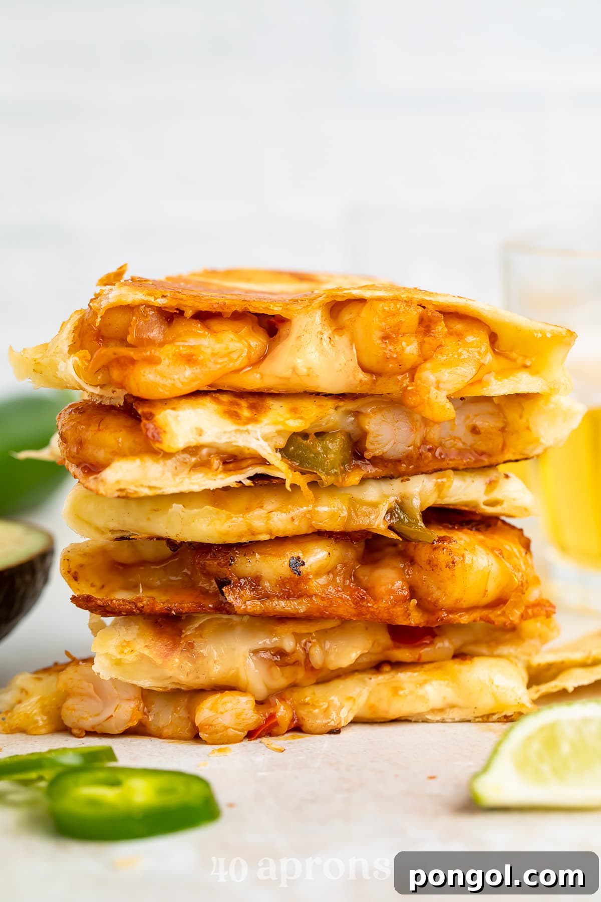 Shrimp quesadilla wedges stacked on top of each other with melted cheese oozing out the sides, garnished with cilantro.