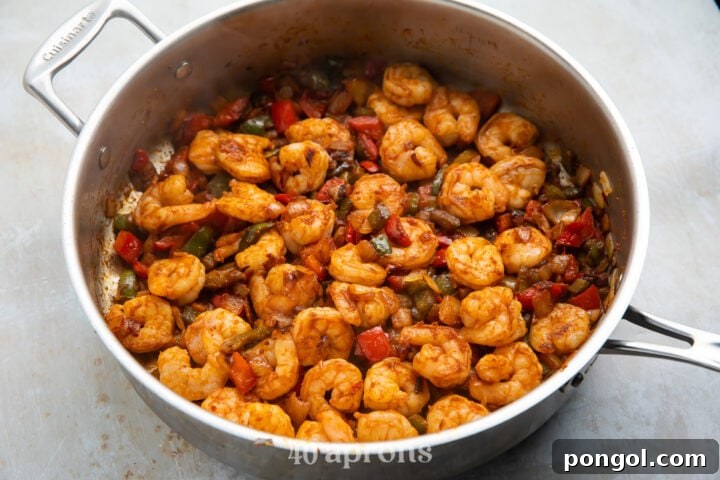 Shrimp and vegetables cooking together in a large skillet for shrimp quesadilla filling.