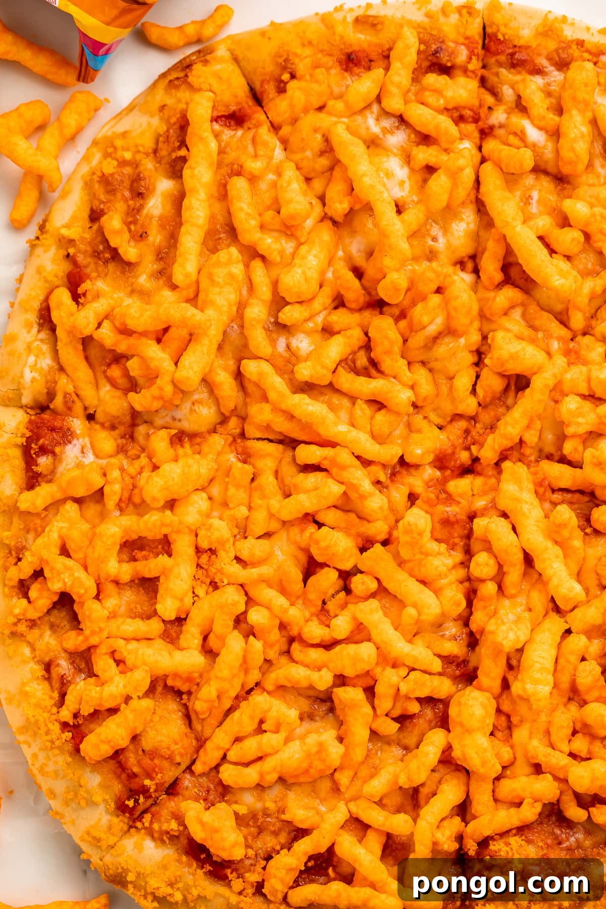 A large, perfectly round cheese pizza adorned with a vibrant layer of crunchy orange Cheetos, sliced into triangles but still presented as a whole pie, ready to be enjoyed.