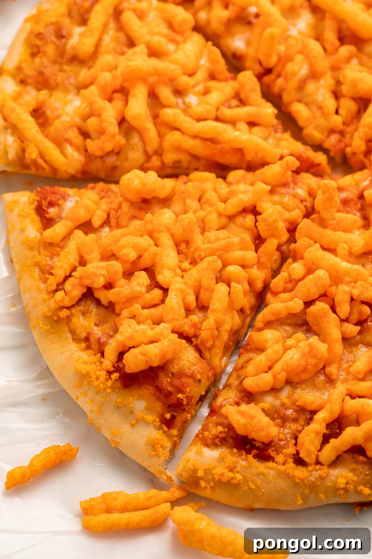 An inviting angled view of a whole, round cheese pizza liberally topped with bright orange, crunchy Cheetos, ready to be devoured.