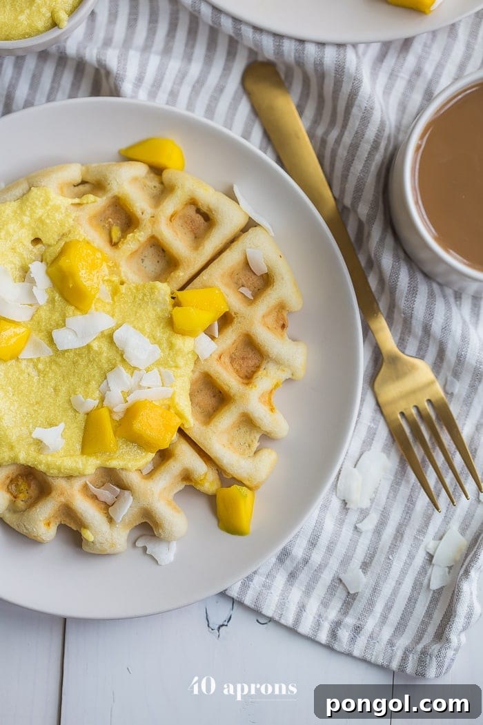 Close-up of golden paleo waffles generously slathered with sweet mango coconut cream.