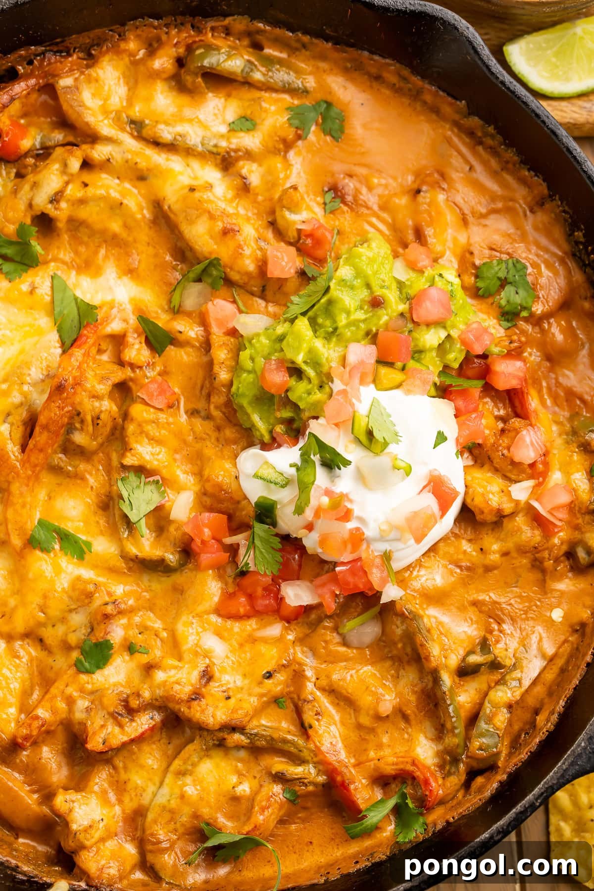 Fajita Fiesta Bake 2 Creamy Chicken Fajita Casserole with vibrant peppers and onions, garnished with sour cream in a rustic cast-iron skillet.