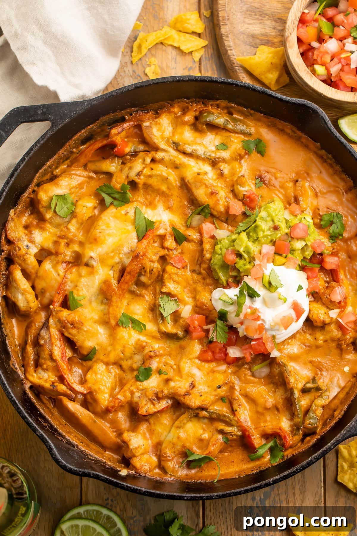 Fajita Fiesta Bake 3 Chicken fajita casserole with a creamy sauce and a dollop of sour cream in a cast-iron skillet, ready to serve.