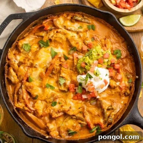 Fajita Fiesta Bake 4 Chicken fajita casserole with a creamy sauce and a dollop of sour cream in a cast-iron skillet.