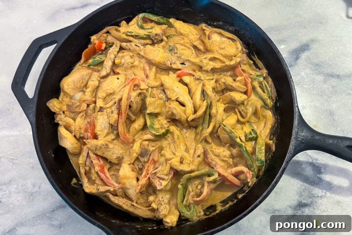 Fajita Fiesta Bake 6 Chicken fajita casserole mixture evenly spread in a cast-iron skillet, ready for cheese.