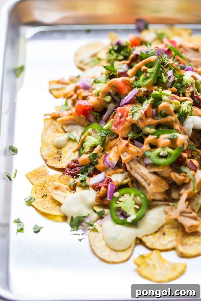 A close-up view of the layered paleo nachos, highlighting the texture of the tender carnitas and creamy sauces.