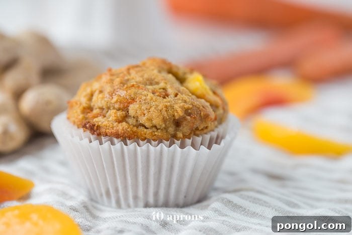 A close-up of a perfectly baked peach ginger paleo muffin, showcasing its golden-brown top and soft texture.