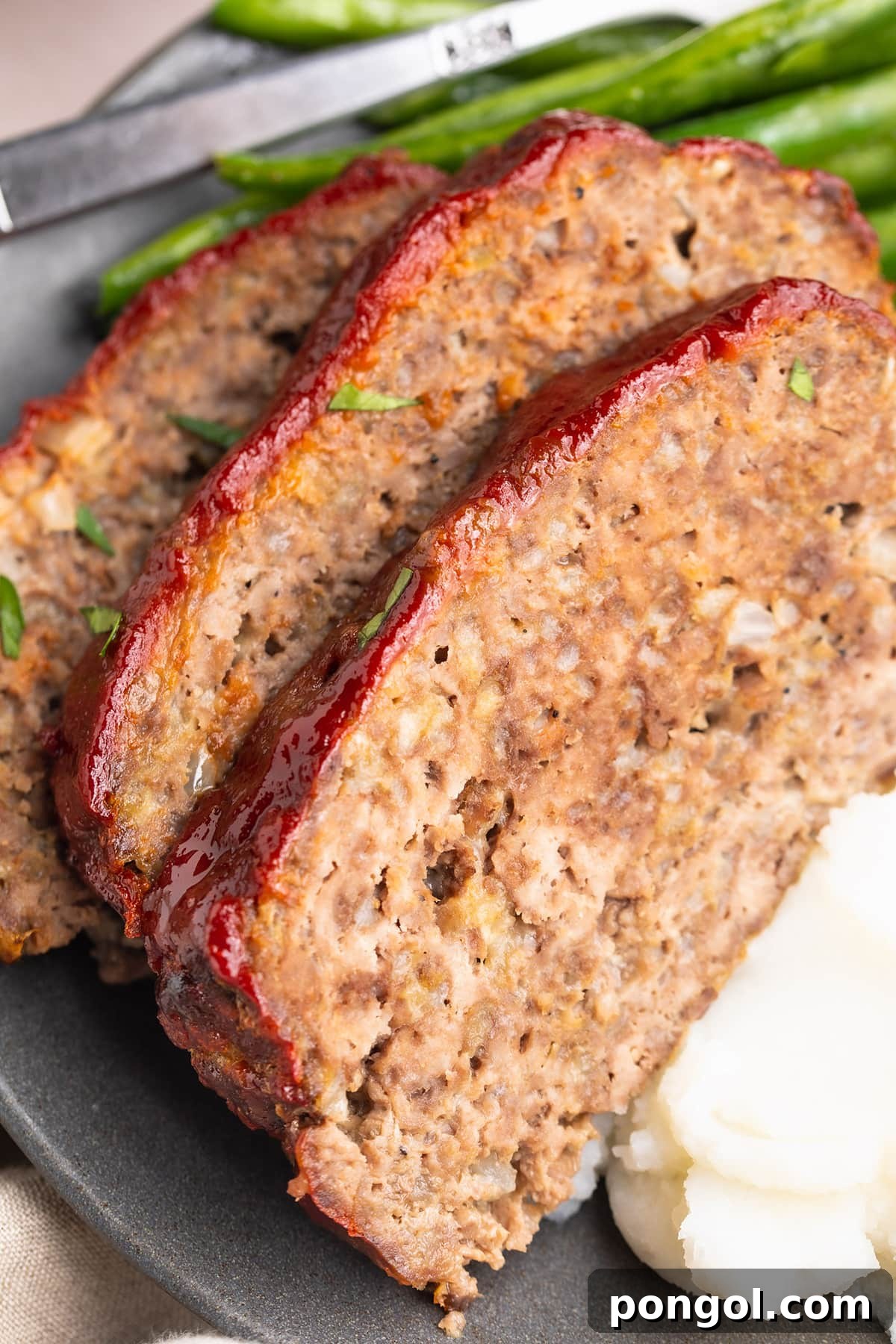 Hearty Gluten-Free Meatloaf 3 Close-up look at three slices of gluten-free meatloaf topped with red ketchup.