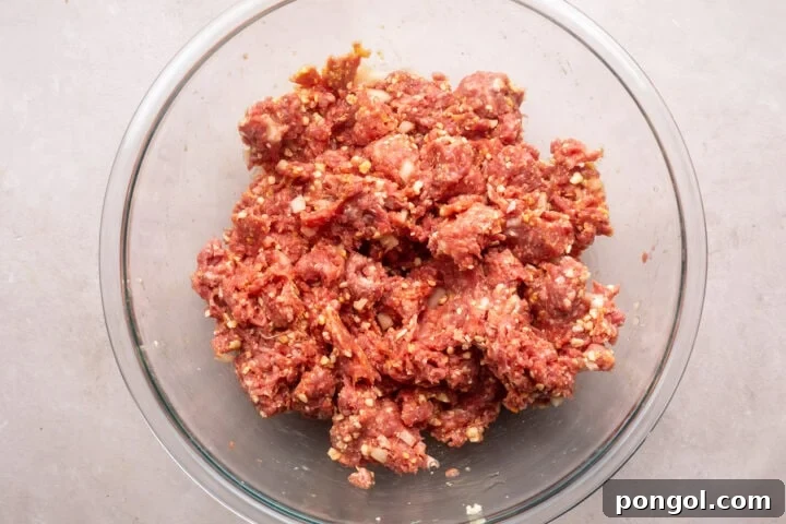 Hearty Gluten-Free Meatloaf 4 Ground beef mixture for gluten-free meatloaf in a large glass mixing bowl.
