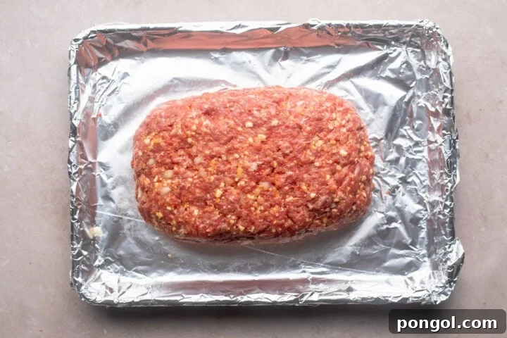 Hearty Gluten-Free Meatloaf 5 Ground beef mixture formed into loaf shape on a baking sheet lined with aluminum foil.