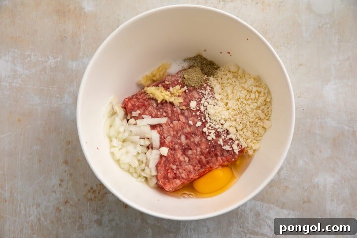 Gyro meatball ingredients added to a medium white mixing bowl, shown before mixing everything together.