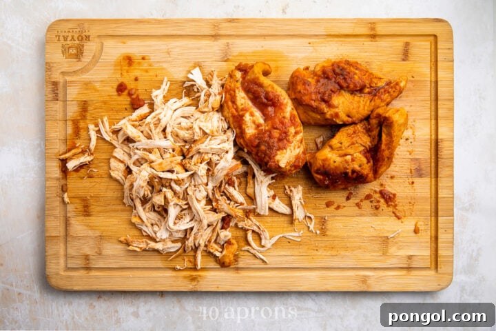 Shredded salsa chicken on a light wooden cutting board.