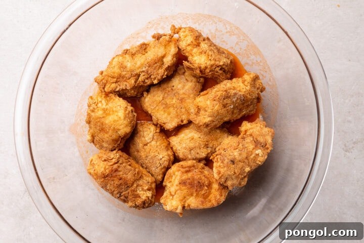 Golden Chicken Bites 9 Breaded, fried boneless chicken wings without buffalo sauce in a large glass mixing bowl.