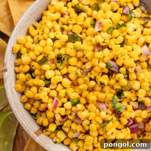 A bowl of roasted chili corn salsa surrounded by tortilla chips.