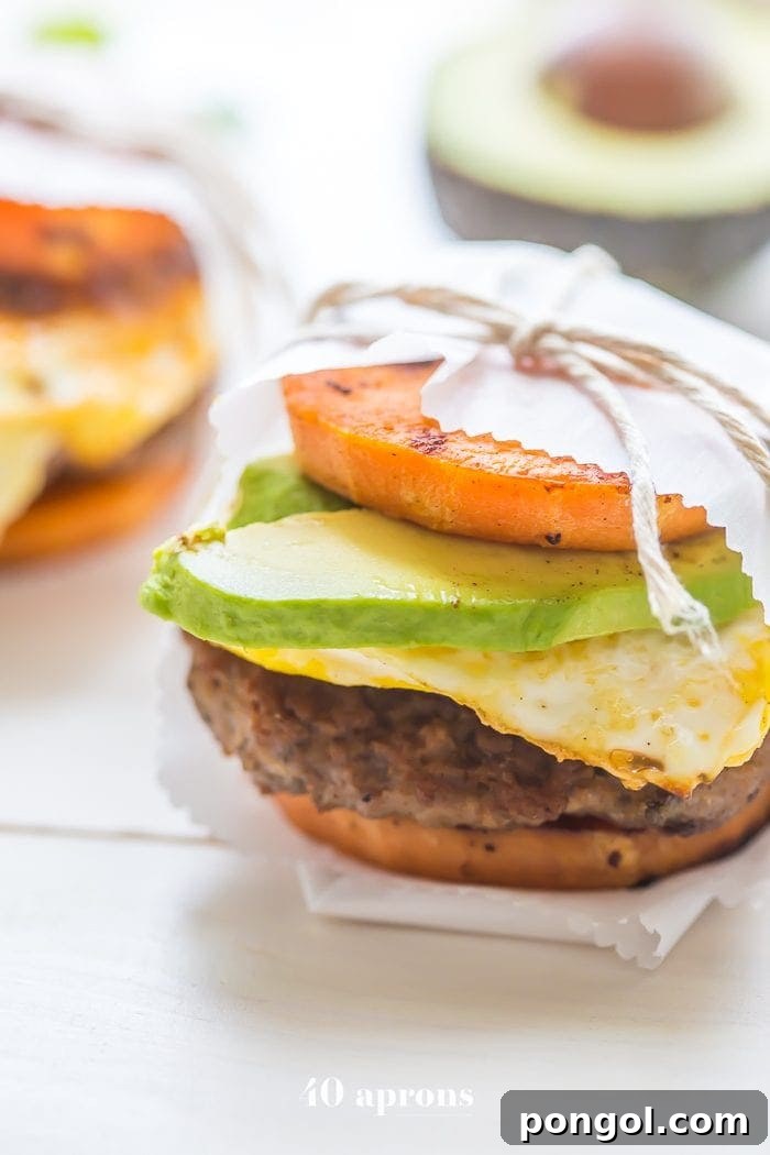 Stacked Whole30 breakfast sandwich showcasing sweet potato bun, sausage, egg, and avocado