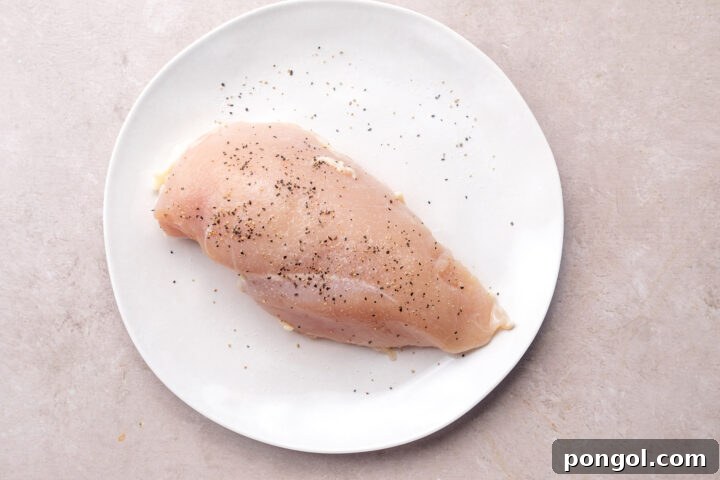 Seasoned chicken breast on a large white round plate.
