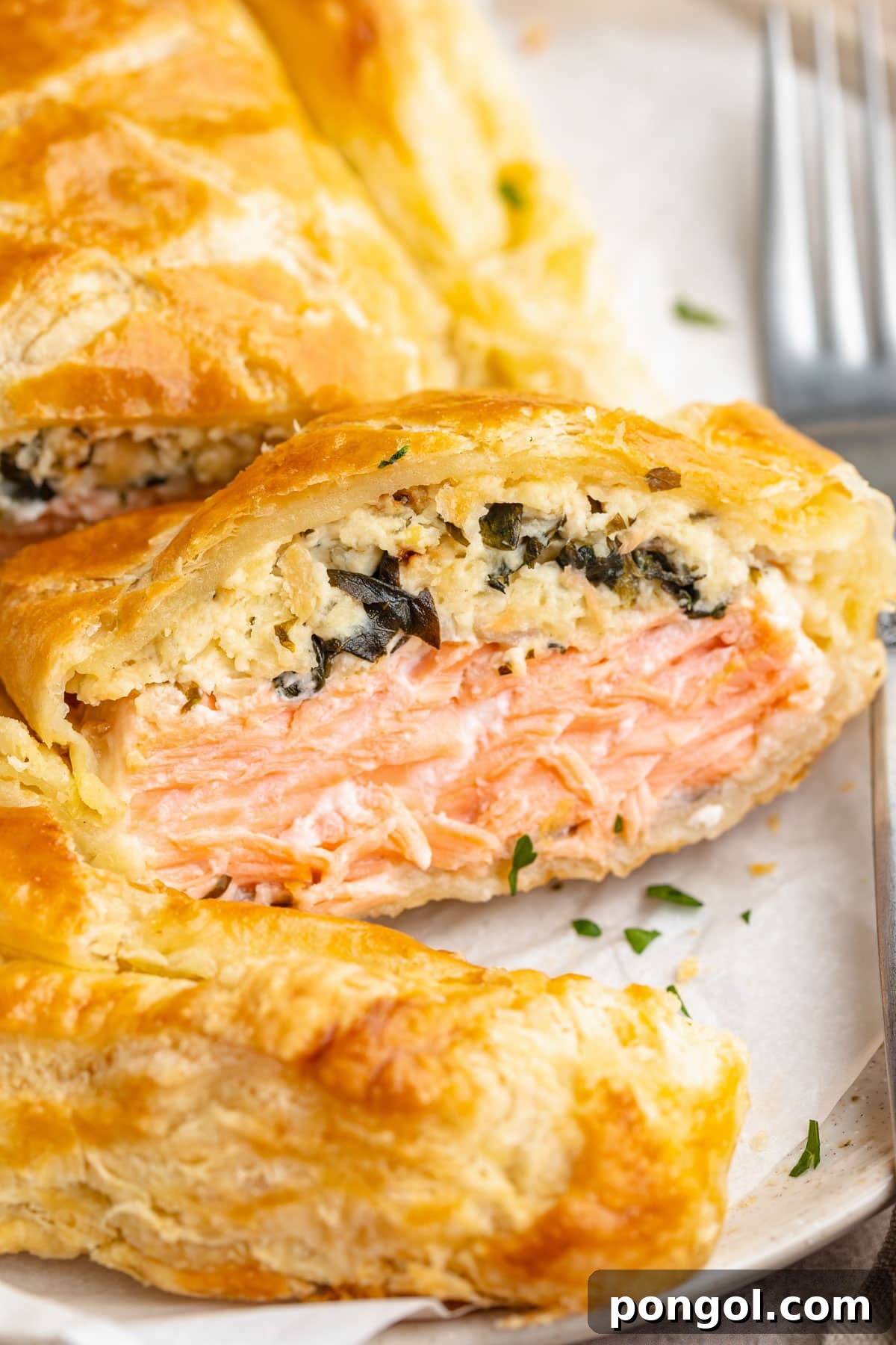Close up of a slice of salmon wellington, positioned on its side to show the salmon filling.