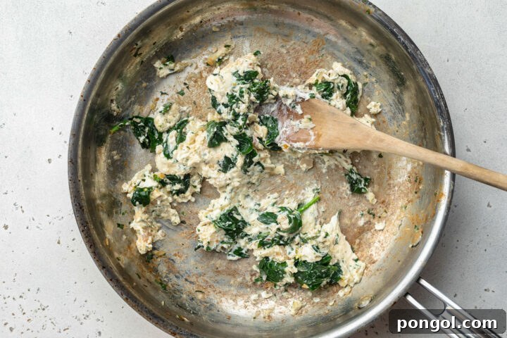 Cream cheese spinach filling for Salmon Wellington in a large skillet.