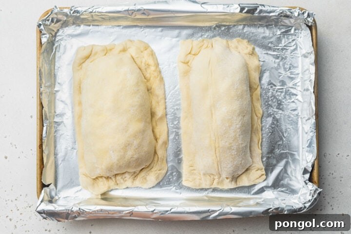 Two salmon fillets fully encased in puff pastry sheets, pinched closed around the edges.