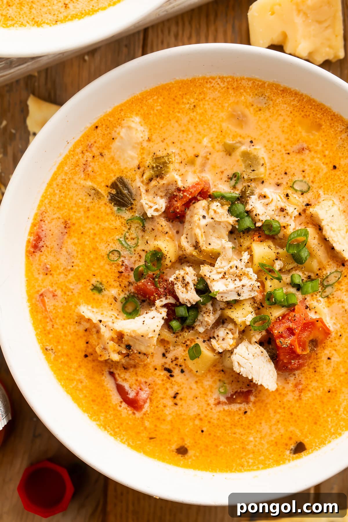 Overhead view of a bowl of Instant Pot creamy cajun chicken pasta soup on a wooden table.