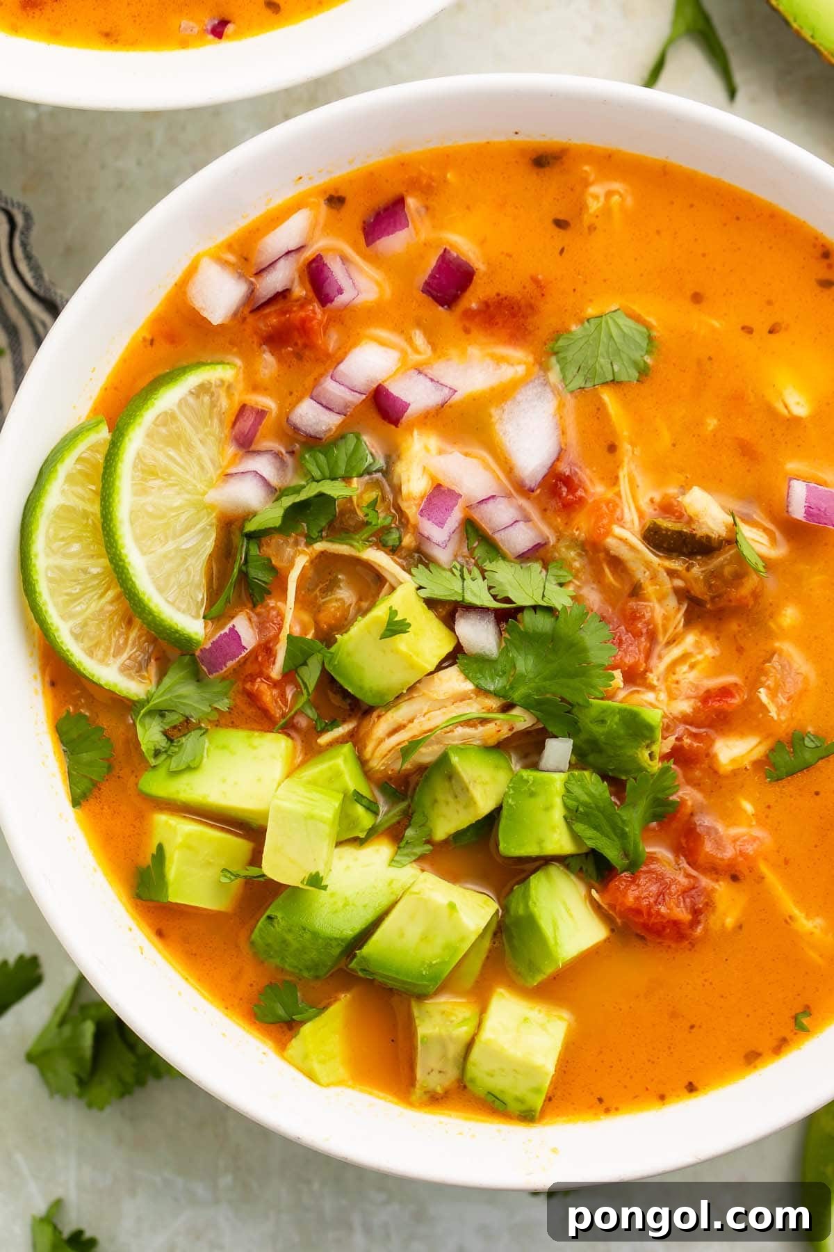 A close-up of a bowl of Whole30 chicken tortilla-less soup on a table, showing the vibrant ingredients.