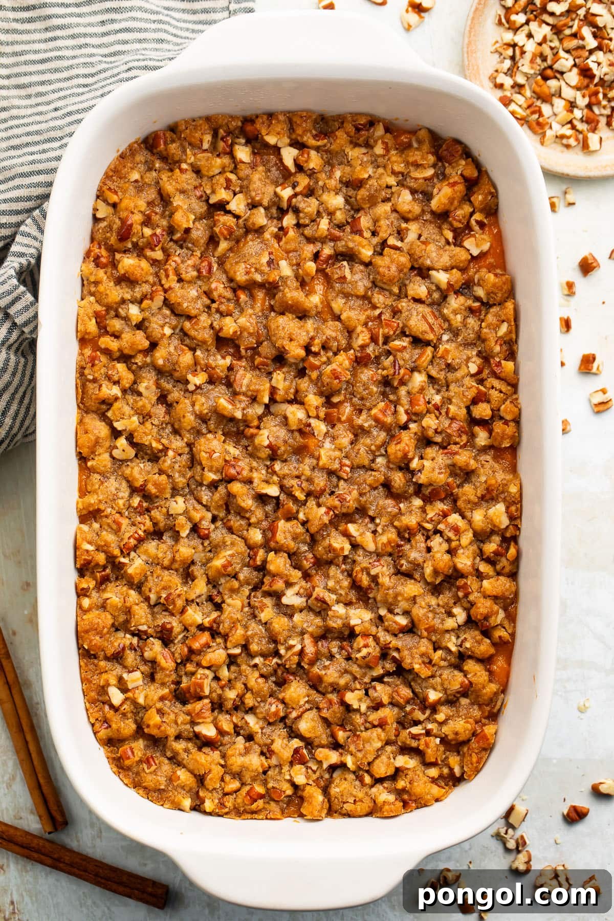 Ruth's Chris Signature Sweet Potato Casserole 2 A golden-brown casserole dish filled with Ruth's Chris Sweet Potato Casserole, generously topped with a rich praline pecan crumble and a glistening brown sugar glaze. Ready to be served.