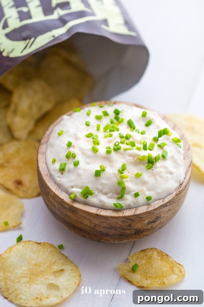 Hand reaching for Kettle Brand Avocado Oil Potato Chips next to a bowl of Paleo French Onion Dip.