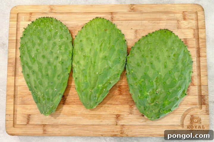 Three nopales paddles on a cutting board, knobs and spines removed.