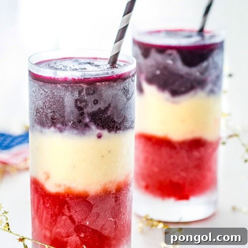 Two tall glasses containing red, white, and blue layered cocktails, ready to be served.
