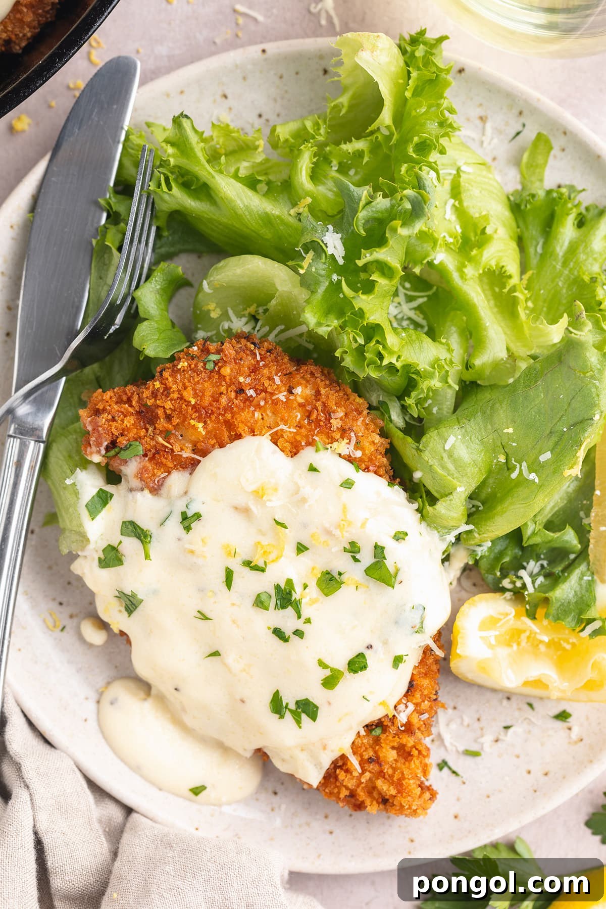 Chicken Romano served on a plate with a fresh green salad, highlighting its golden crust and creamy sauce.