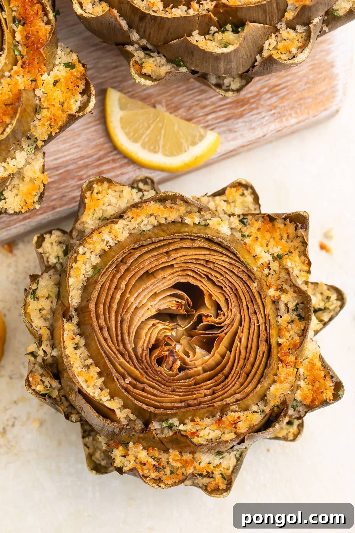 Gourmet Stuffed Artichokes 3 Top-down look at a stuffed artichoke, with breadcrumb stuffing packed between each row of petals and baked until golden.