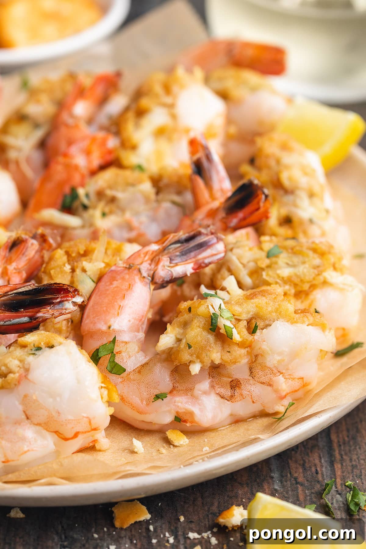 A plate of perfectly baked, golden-brown stuffed shrimp, garnished with fresh lemon wedges and a sprinkle of vibrant green herbs, ready to be served.