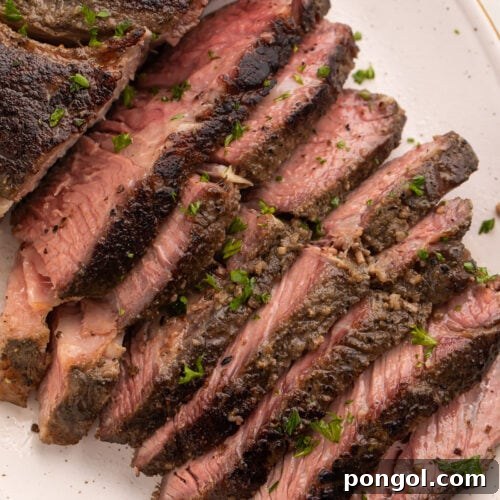 Overhead photo of sous vide chuck roast on a white platter, with half the chuck roast sliced into thin strips and fanned out to show the crust and the inside of the roast.