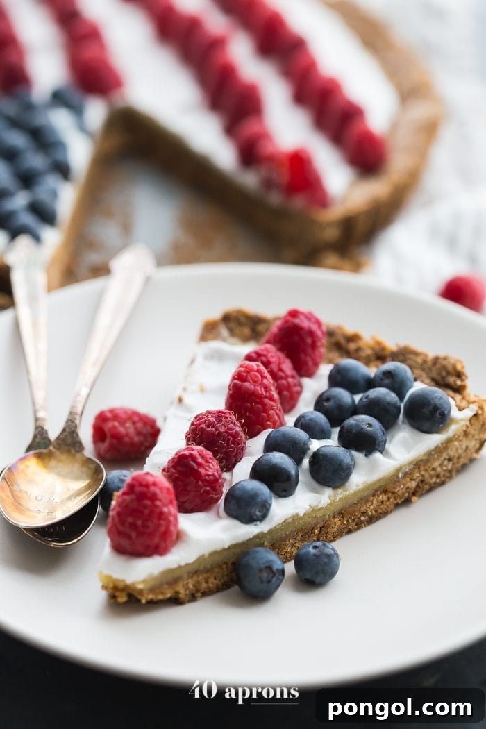 Close-up of the perfectly baked shortbread crust and almond frangipane filling of a Paleo Flag Fruit Tart, topped with creamy coconut and patriotic berries.