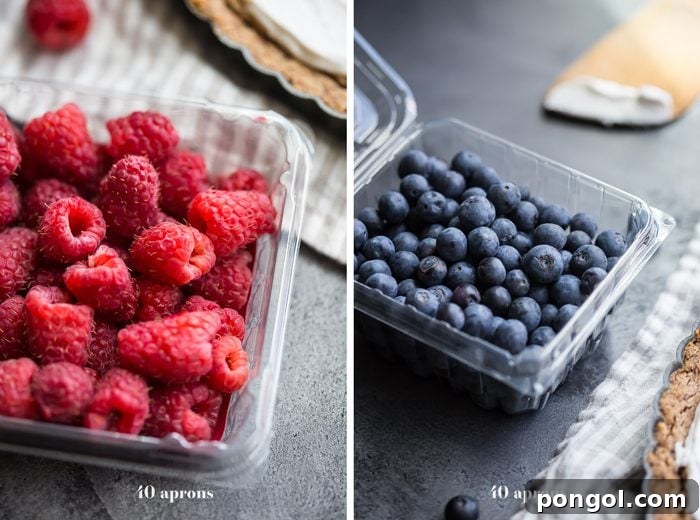 A slice of Paleo Flag Fruit Tart showcasing the layers: crisp coconut oil shortbread, smooth almond frangipane, and a generous topping of coconut cream and fresh berries.