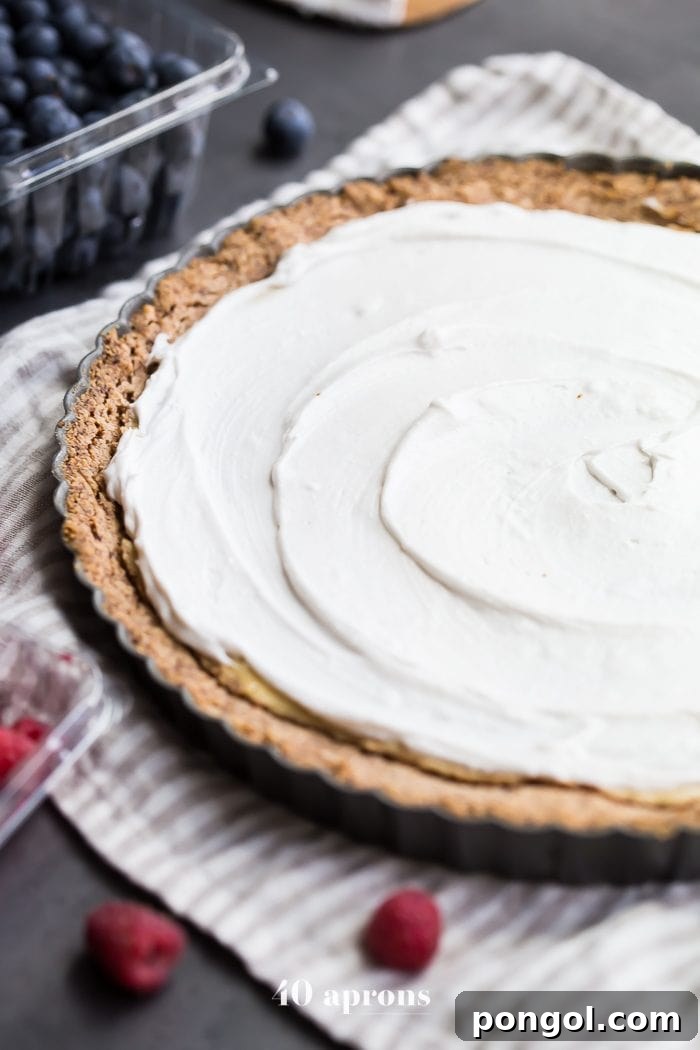 Overhead shot of a beautiful Paleo Flag Fruit Tart, meticulously decorated with blueberries and raspberries to form an American flag, perfect for a healthy Fourth of July dessert.