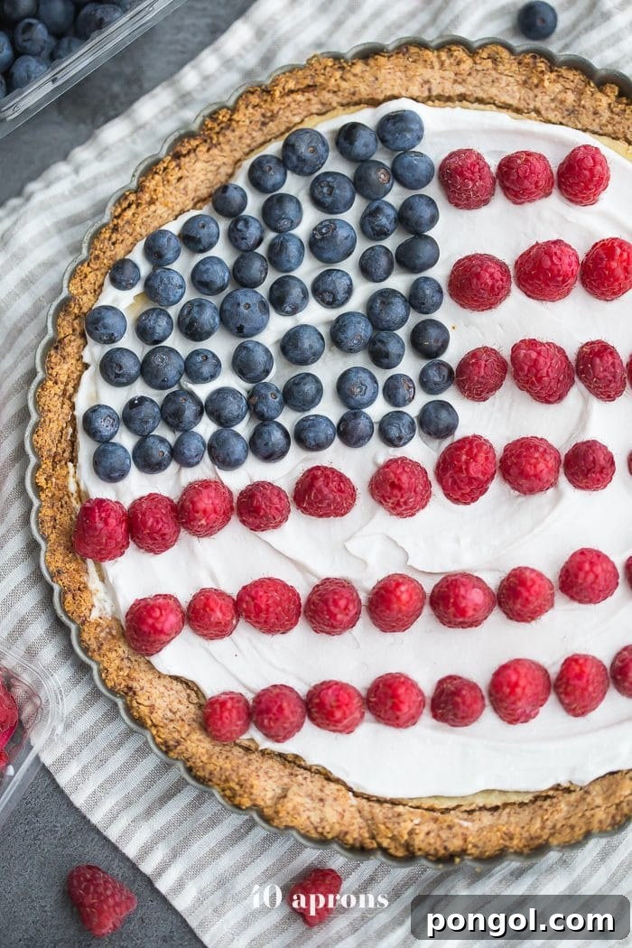 A patriotic Paleo Flag Fruit Tart with a creamy white topping, decorated with fresh blueberries for the stars and raspberries for the stripes of the American flag.