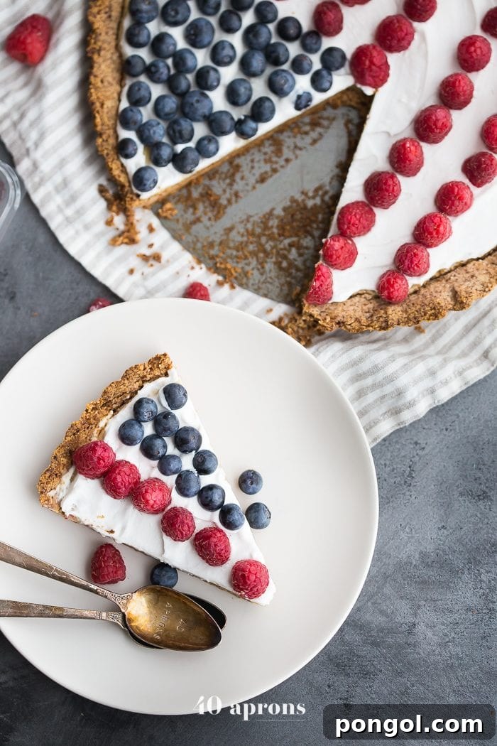 A beautifully presented Paleo Flag Fruit Tart, highlighting the vibrant colors of fresh berries against a smooth, white coconut cream base, perfect for a healthy summer celebration.