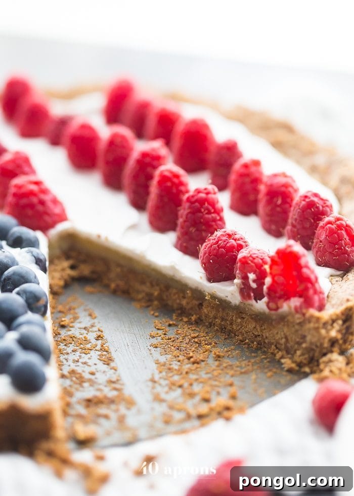 Close-up on a slice of Paleo Flag Fruit Tart, showing the rich texture of the almond frangipane and the golden-brown shortbread crust beneath the fresh fruit topping.