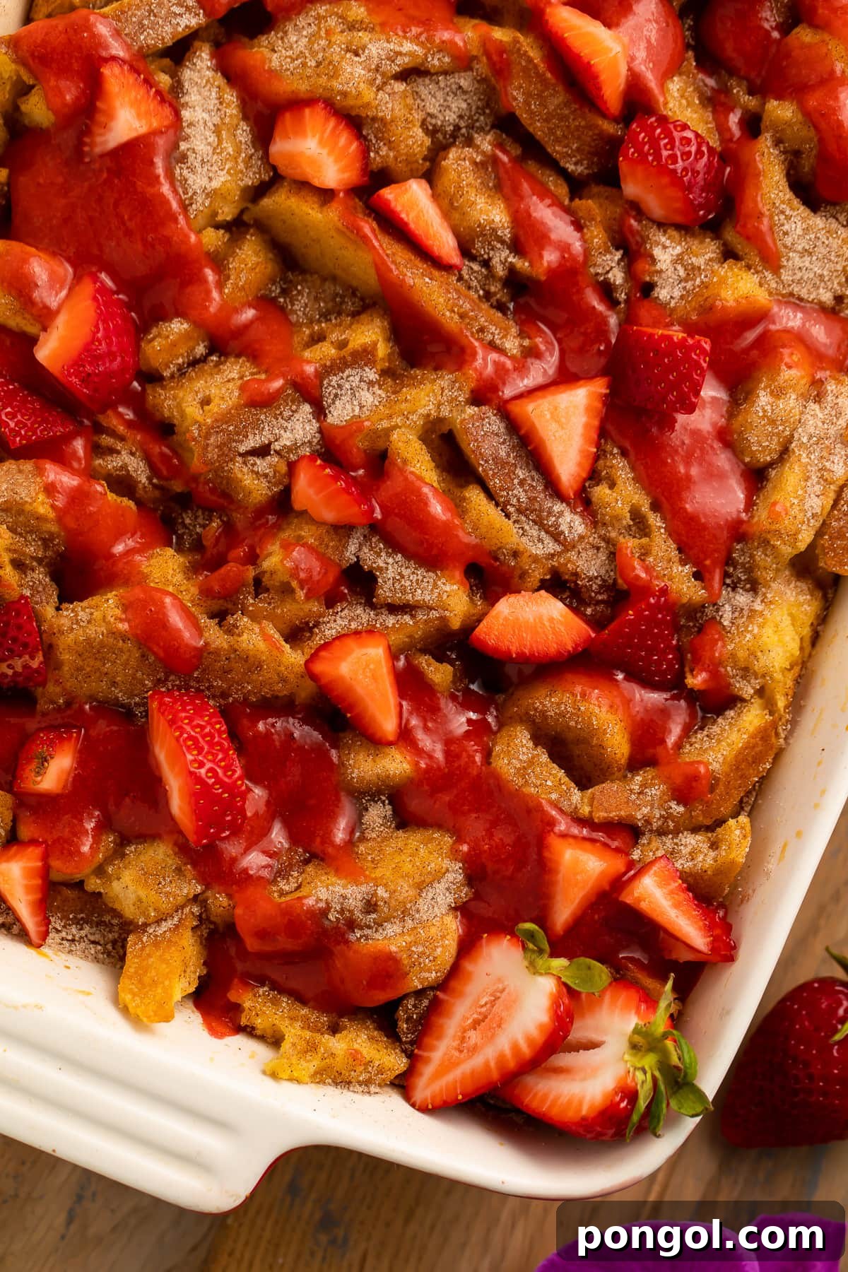 30 Festive Casseroles Your Holiday Table Needs 11 A casserole dish, angled on a table, filled with banana stuffed french toast casserole topped with strawberries.