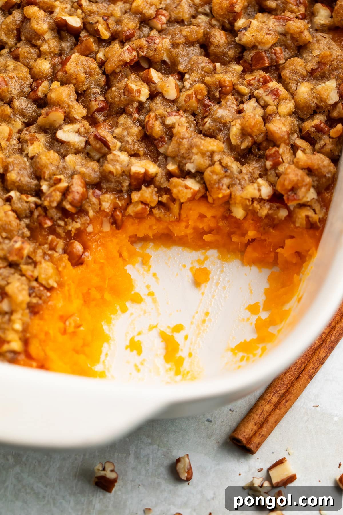 30 Festive Casseroles Your Holiday Table Needs 15 A casserole dish of Ruth's Chris sweet potato casserole topped with pecans and brown sugar, with a scoop of casserole missing from the corner of the dish.