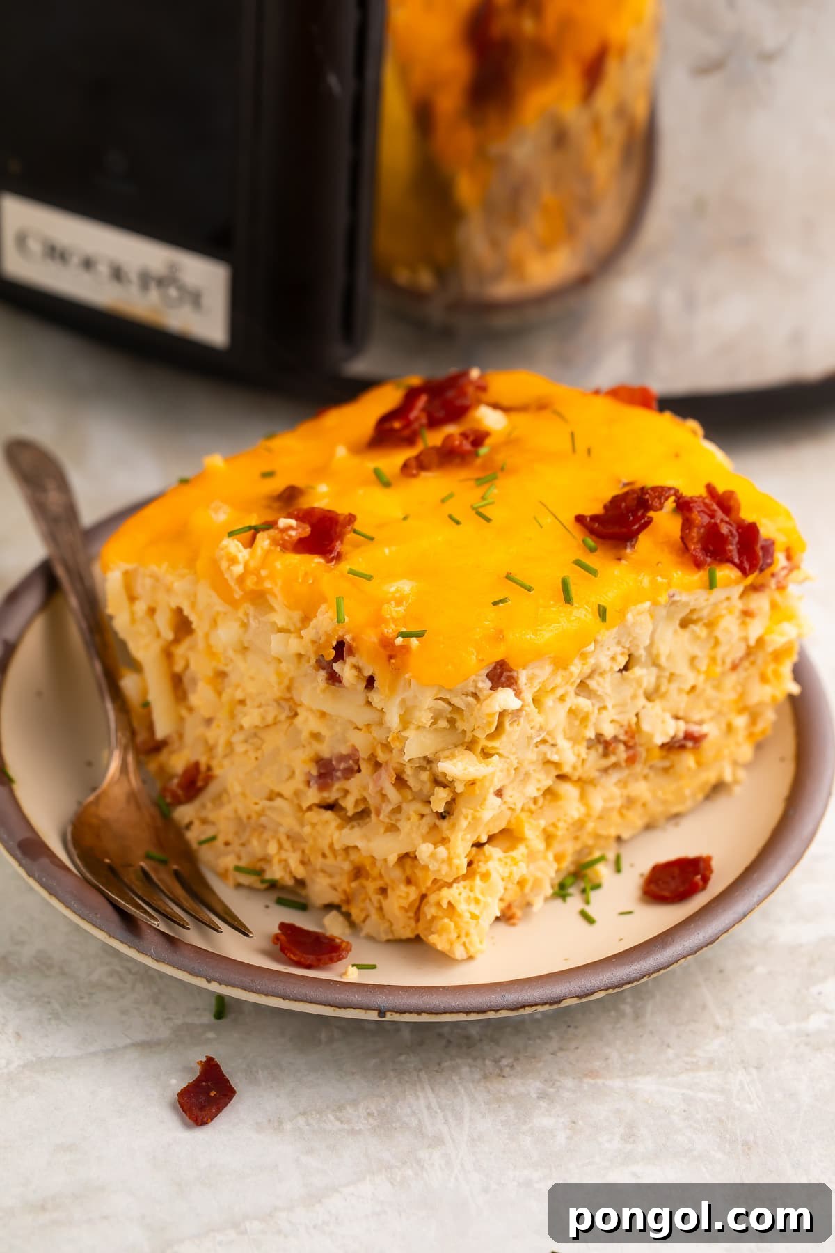30 Festive Casseroles Your Holiday Table Needs 3 A square, multi-layered slice of Crockpot breakfast casserole on a plate in front of a slow cooker.