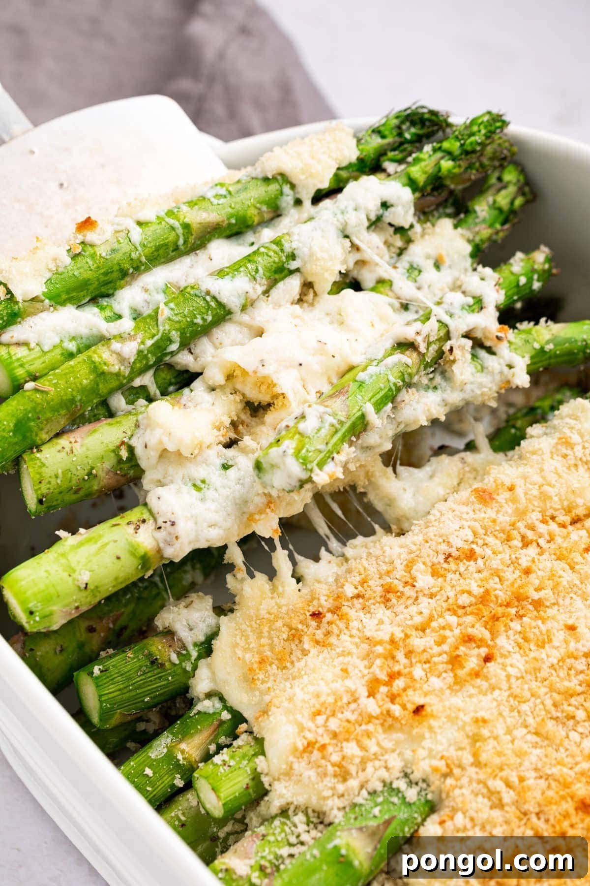 30 Festive Casseroles Your Holiday Table Needs 22 Asparagus casserole being scooped out of the baking dish with a spatula.