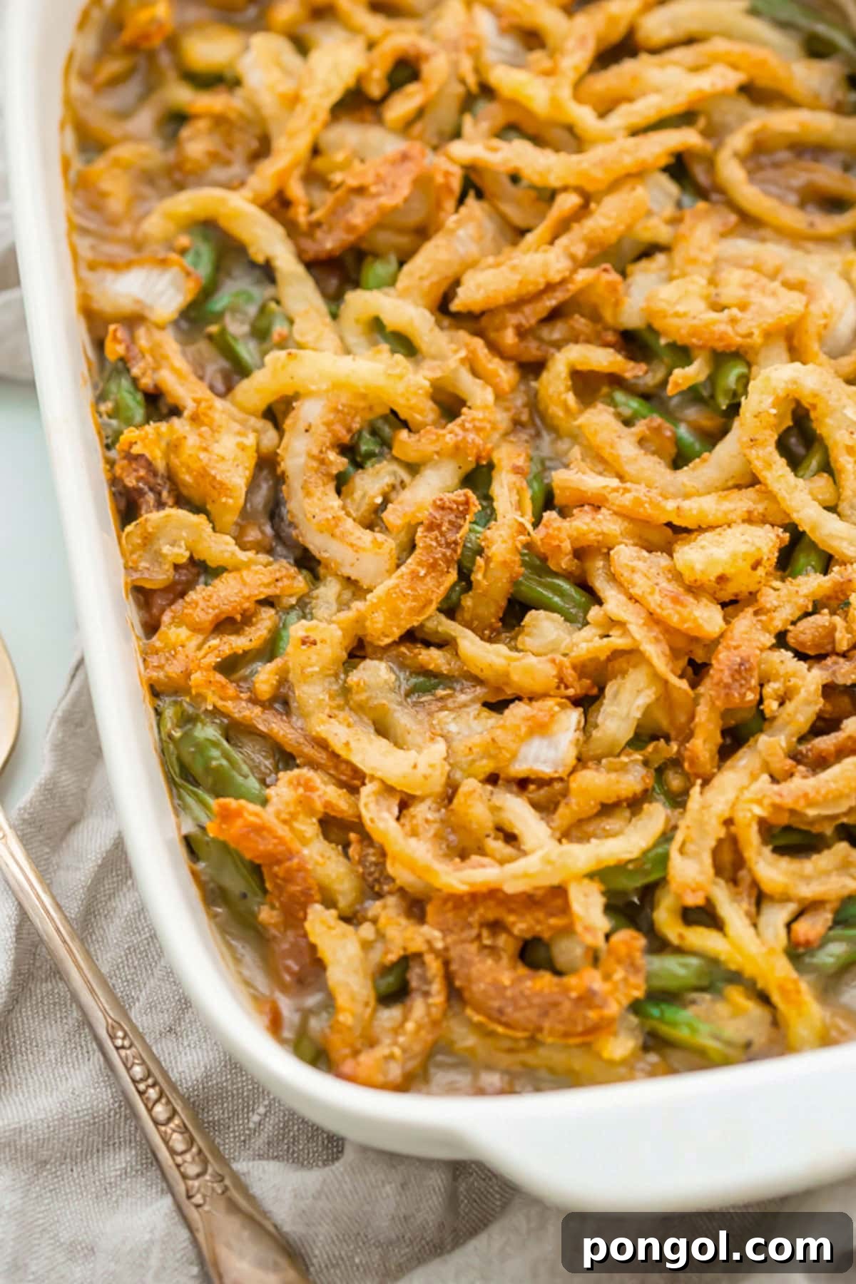 30 Festive Casseroles Your Holiday Table Needs 26 A large rectangular casserole dish holding a Whole30 green bean casserole topped with crispy onions.