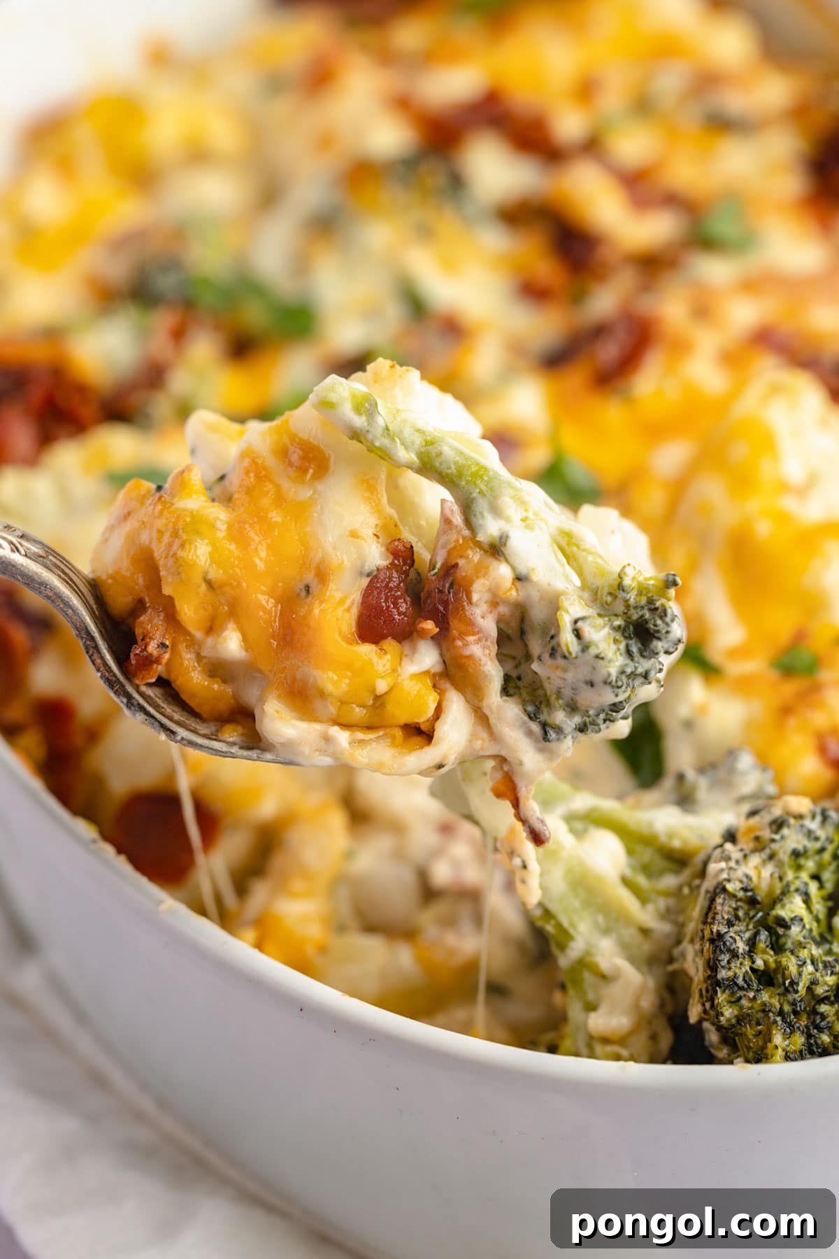 30 Festive Casseroles Your Holiday Table Needs 29 A spoonful of keto broccoli cauliflower casserole being lifted out of a casserole dish.