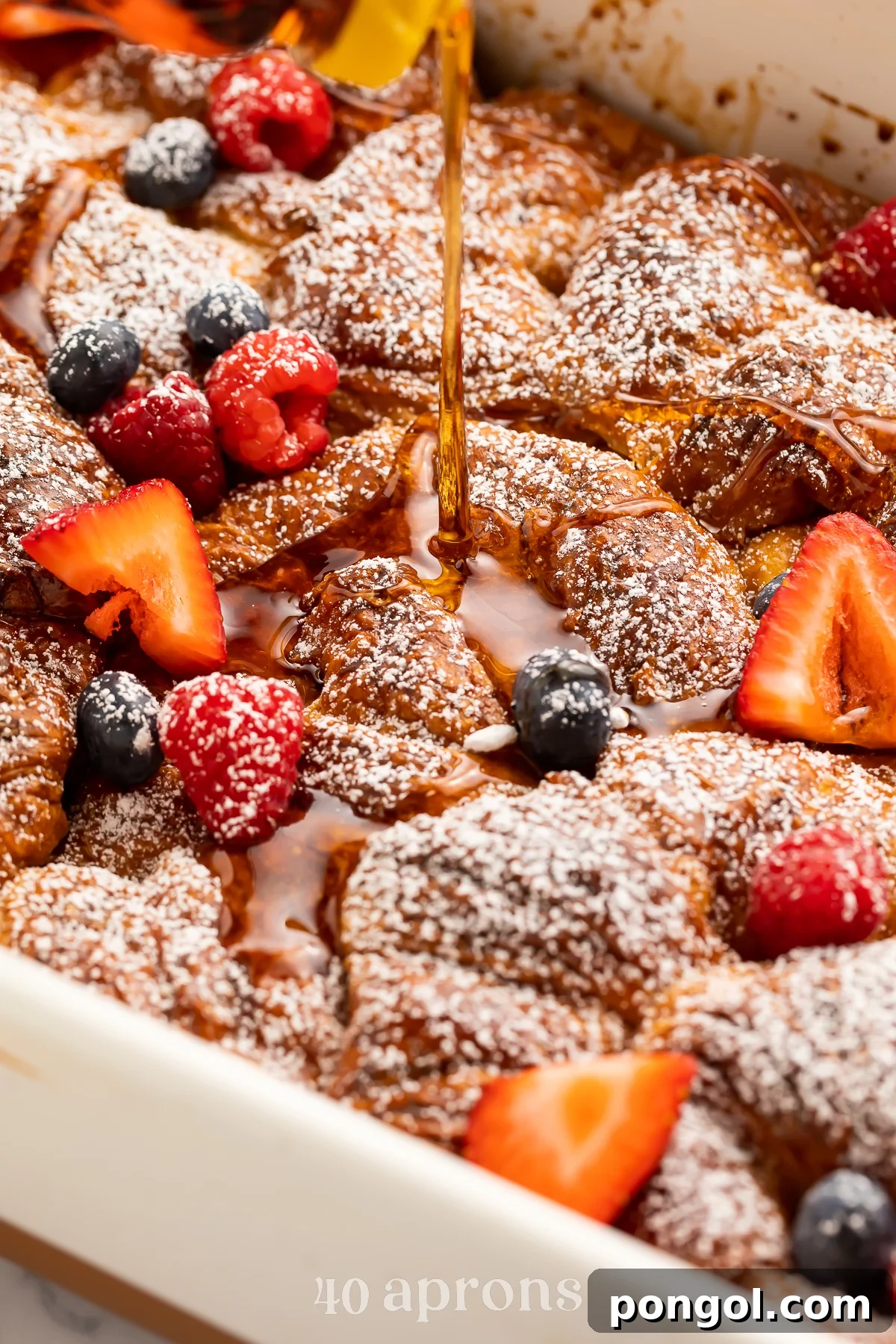 30 Festive Casseroles Your Holiday Table Needs 4 Close-up look at a croissant french toast casserole with brown sugar cinnamon in a casserole dish with strawberries and blueberries.