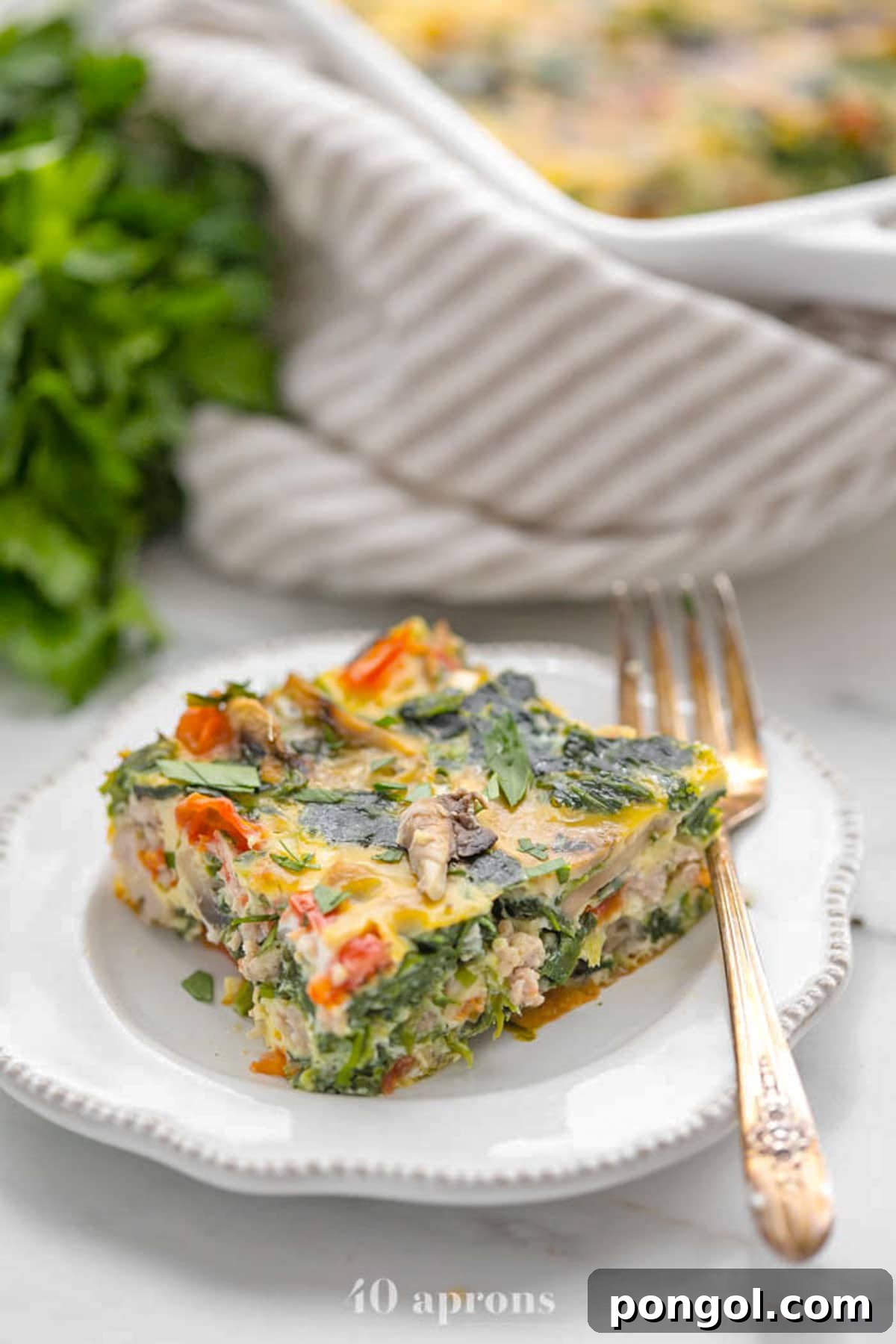 30 Festive Casseroles Your Holiday Table Needs 5 A square of Whole30 sausage, spinach, and mushroom breakfast casserole on a plate.
