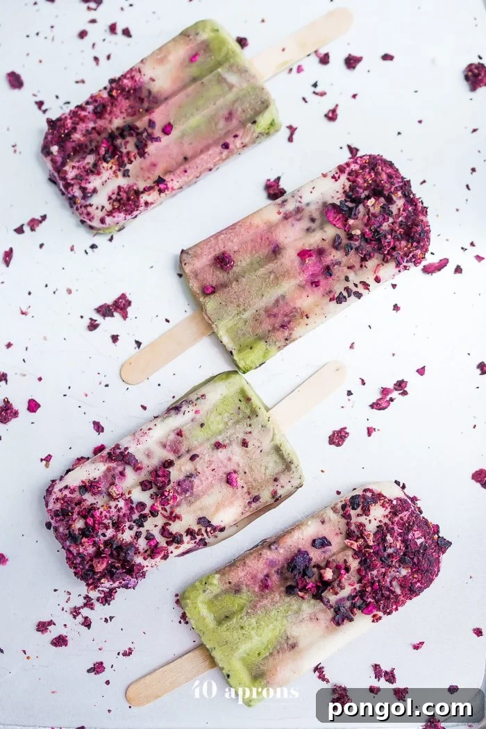 A trio of delicious mermaid popsicles, each with distinct green, white, and purple layers, ready to be enjoyed.