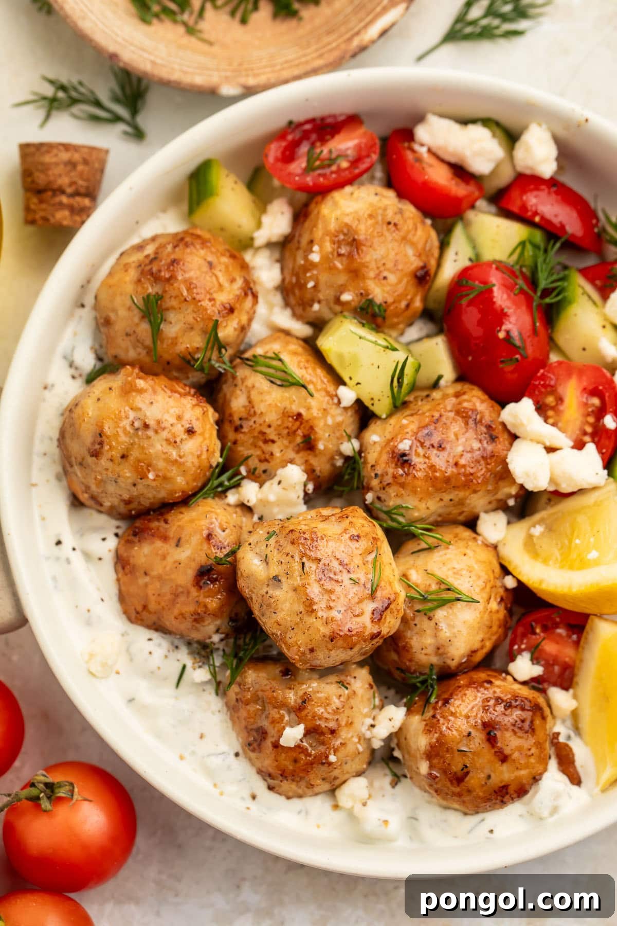 Zesty Greek Chicken Meatballs 2 Top-down photo showing Greek chicken meatballs in a large bowl with rice, feta cheese, veggies, and herbs. A vibrant and appealing meal.