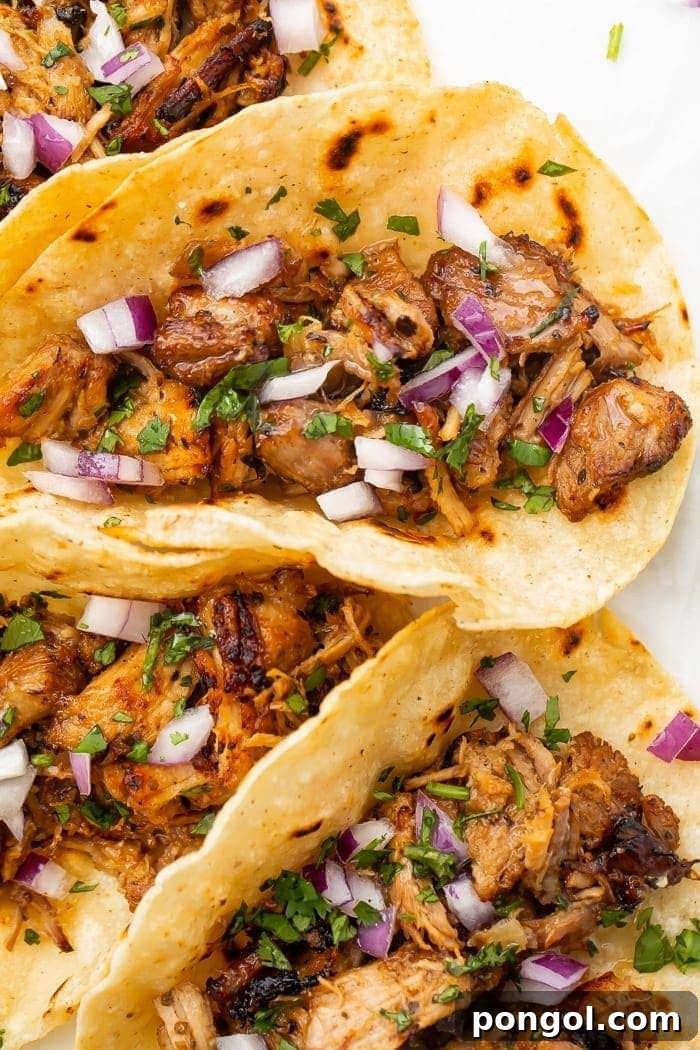 Tortillas filled with Instant Pot carnitas, garnished with cilantro and lime wedges